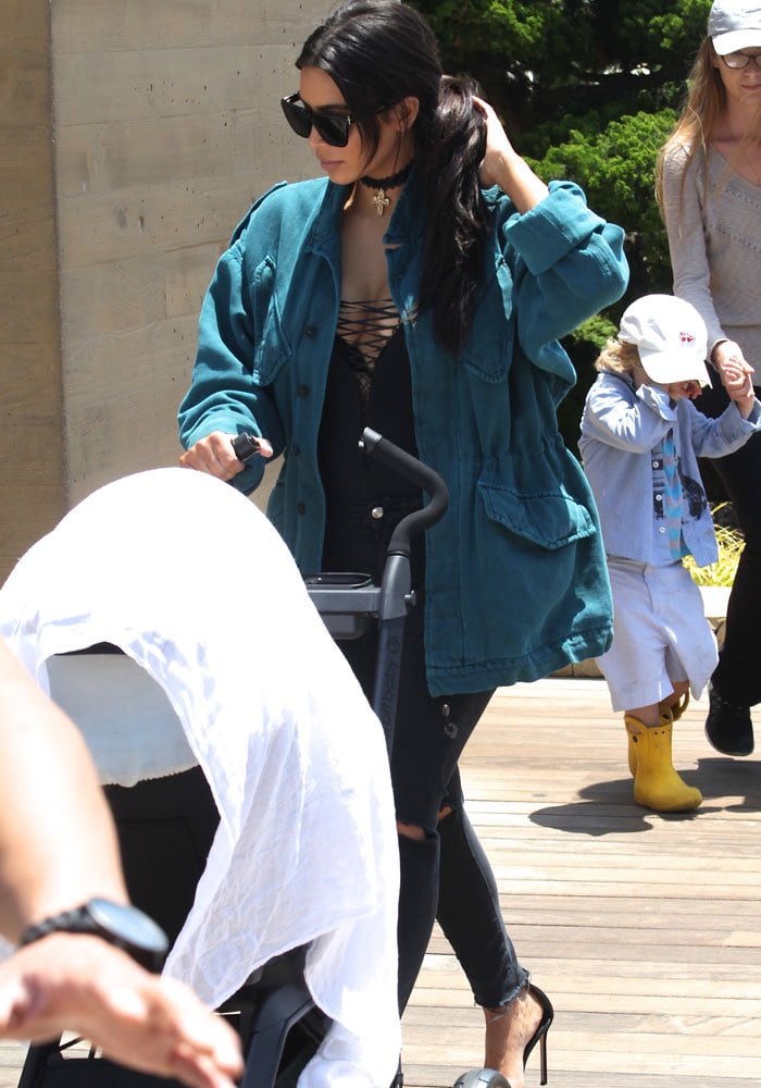 Kim Kardashian wearing an oversized aqua-colored denim jacket over a black lace-up top