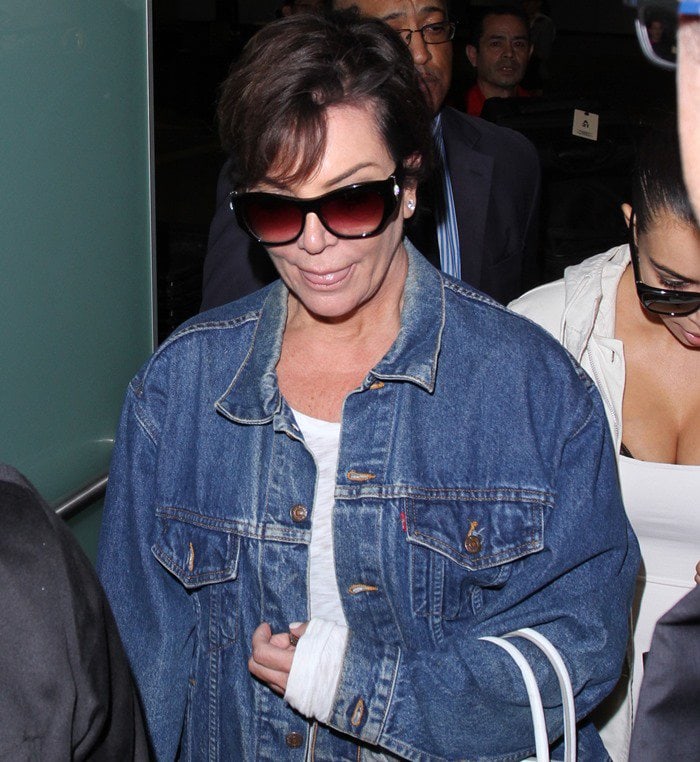 Kris Jenner wears dark sunglasses and a denim jacket as she arrives at the Los Angeles International Airport