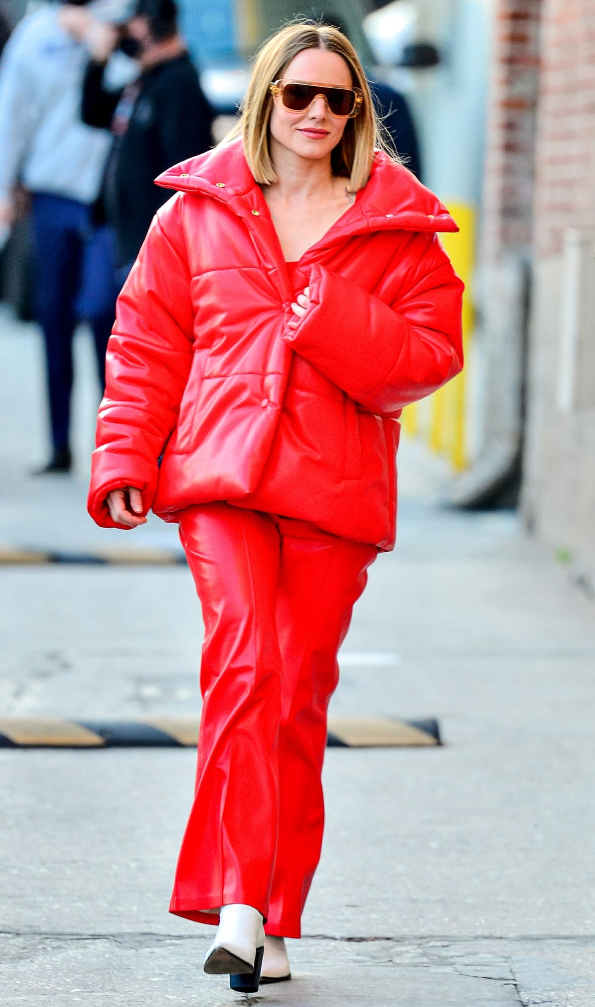 Kristen Bell wears a red puffer jacket and pleated pants by Nanushka when arriving for a taping of Jimmy Kimmel Live!