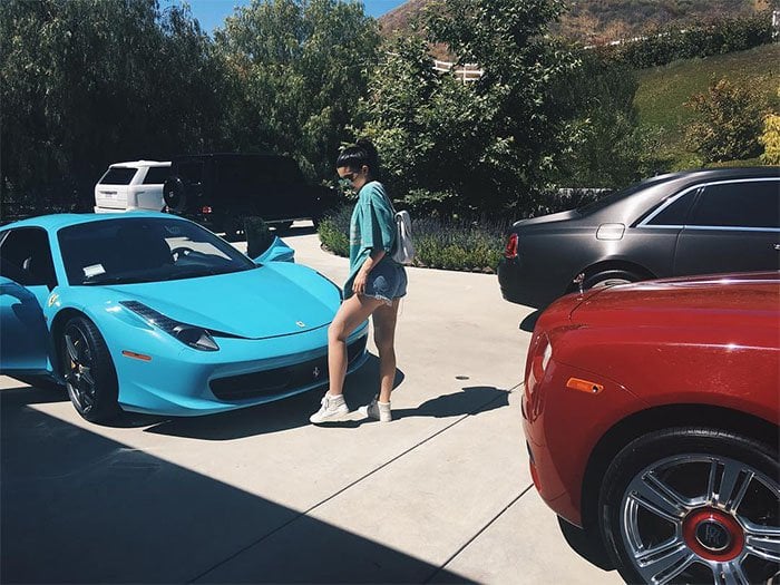 Kylie Jenner wears a "Life of Pablo" t-shirt to show off her blue Ferrari