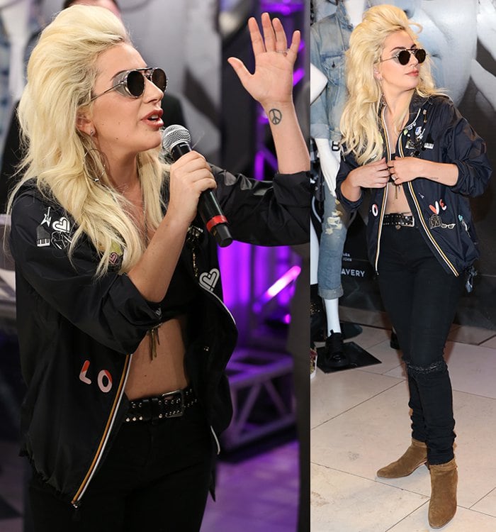 Lady Gaga shows off her peace sign tattoo and flat abs in a patch-embellished jacket and round sunglasses
