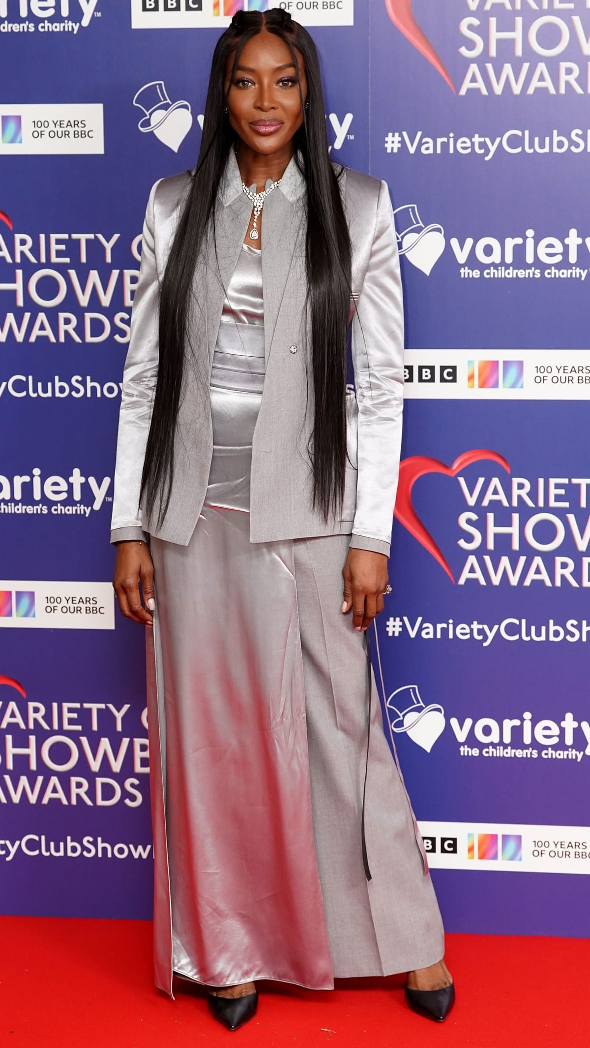 Naomi Campbell styled black patent pumps with a silver jumpsuit underneath a matching blazer from Fendi's Spring 2023 Collection