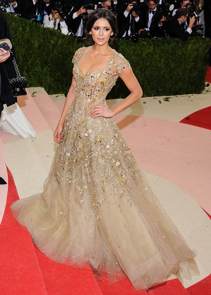 Nina Dobrev's Marchesa gown, adorned with gold jewels and mirrored embellishments, featured sheer illusion tulle layers that revealed a hint of cleavage