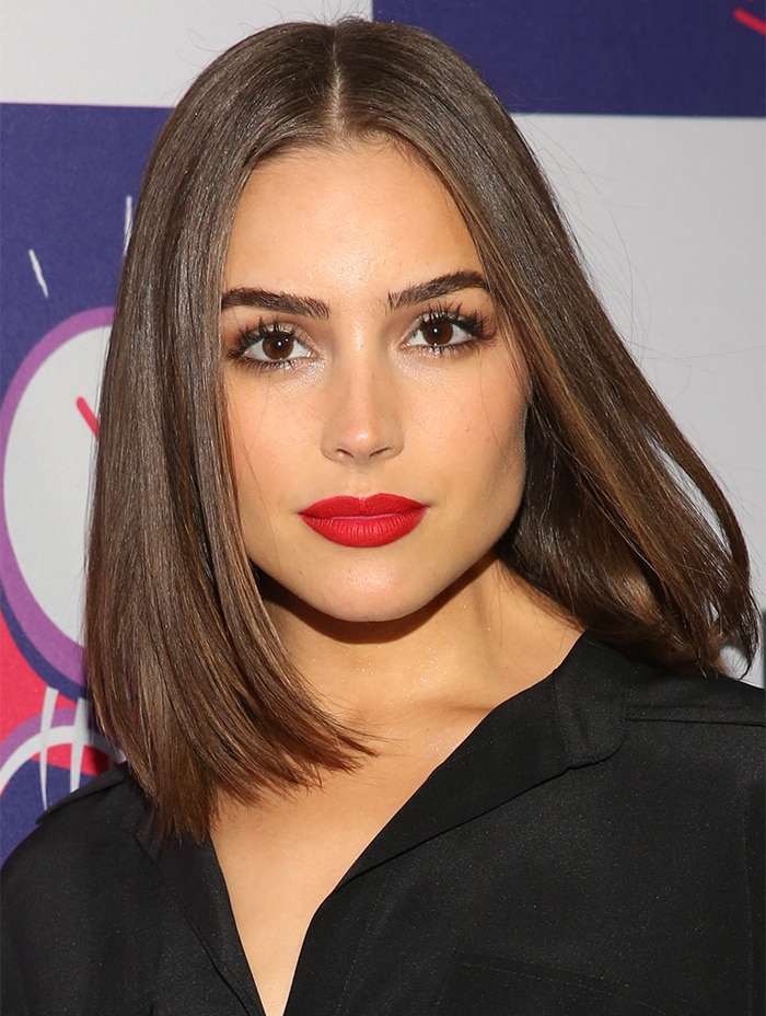 Olivia Culpo's vibrant red lipstick brings a bold pop of color, complementing her sophisticated ensemble