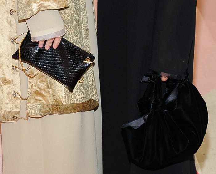 Ashley and Mary-Kate Olsen showcase their signature vintage-inspired elegance at the Met Gala, carrying luxe black clutches—one structured with gold hardware, the other a voluminous velvet pouch—perfectly complementing their ethereal ensembles