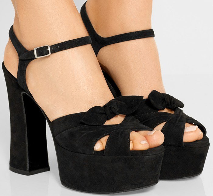 Black suede 'Candy' platform sandals from Saint Laurent featuring a peep toe, crossover straps to the front, a bow on the front, an ankle strap with a side buckle fastening, a platform sole, and a chunky high heel