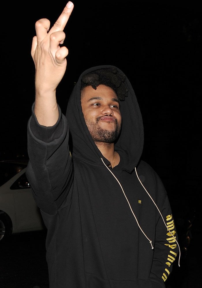 Abel Tesfaye, aka The Weeknd, flicks the paparazzi off as he trails behind girlfriend Bella Hadid