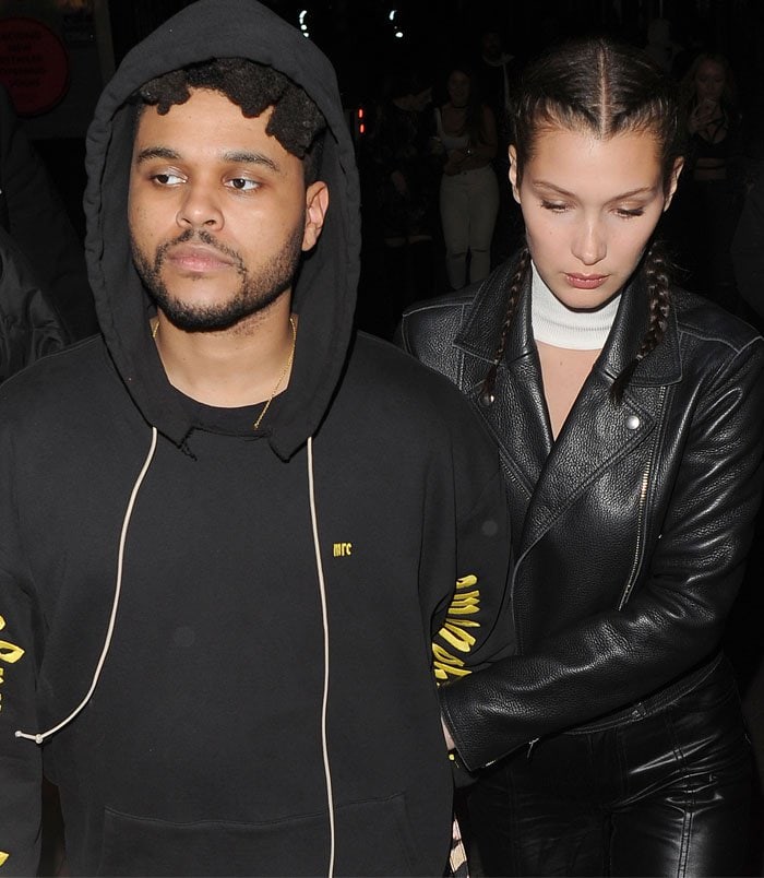 Bella Hadid hides behind her boyfriend Abel Tesfaye ("The Weeknd") as they leave the club at 3 a.m.