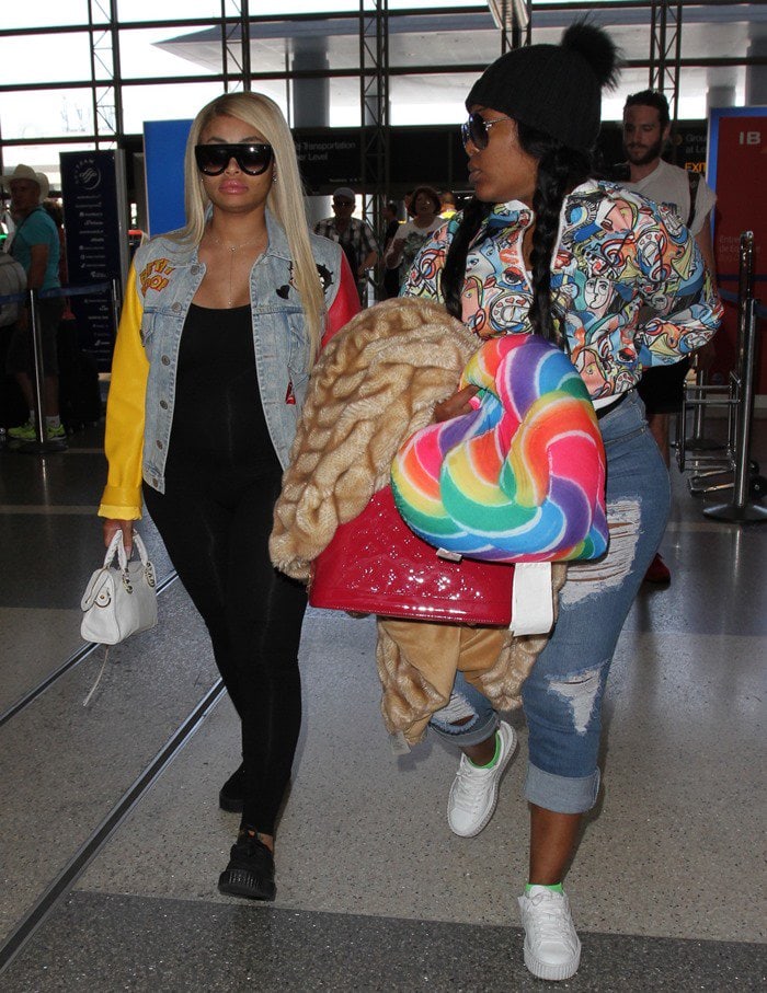 Blac Chyna wears a Betty Boop jacket and black pants as she arrives at LAX with a friend