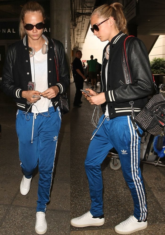 Cara Delevingne wears Adidas track pants as she arrives at LAX