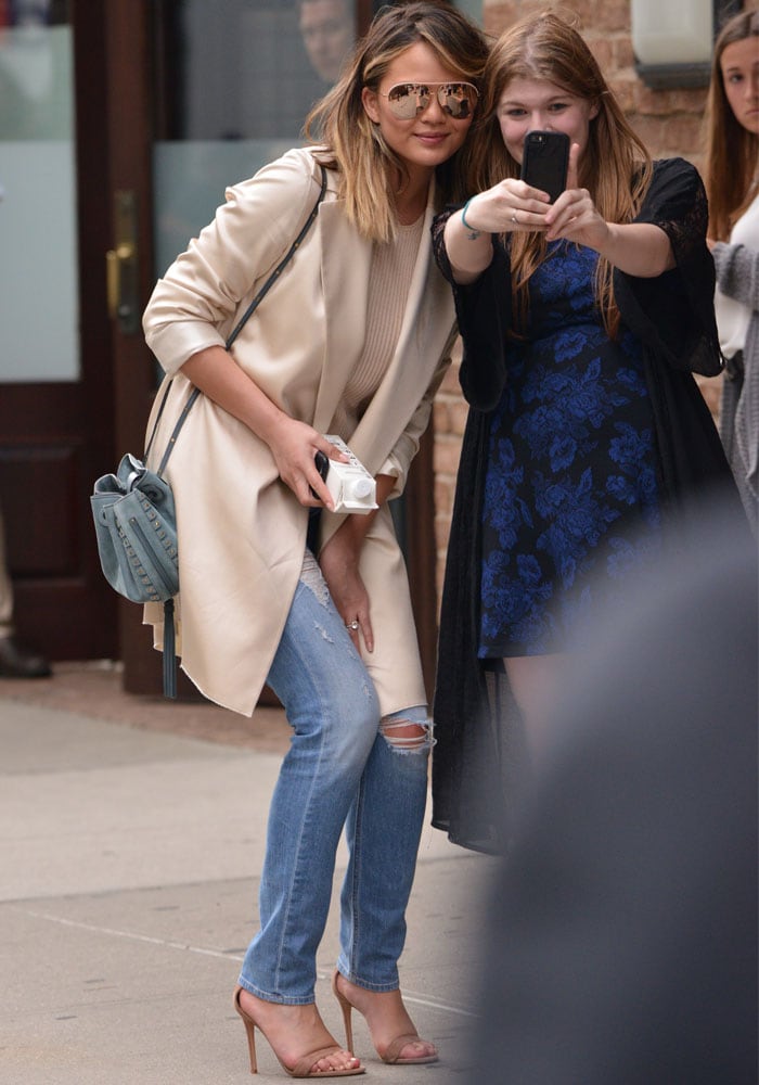 Chrissy Teigen carries a blue Chloé "Inez" drawstring bag while posing with a fan before heading out to the WME-IMG panel