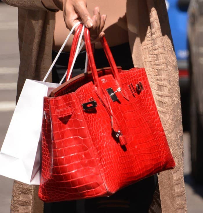 EJ Johnson carries a striking red Hermès Crocodile Birkin—an ultra-luxurious handbag estimated to cost around $100,000, exuding status and sophistication