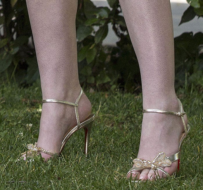 Elle Fanning's perfectly pedicured feet shine in gold Louboutin 'Bat Bat' sandals, complete with height-boosting heels and intricate crystal details