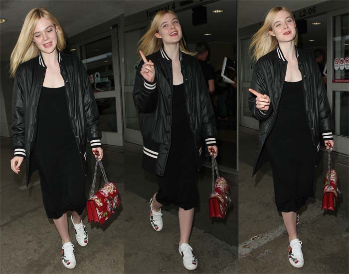 Elle Fanning exudes effortless cool in a black jersey dress, oversized varsity jacket, and vibrant Gucci "Ace" floral-embroidered sneakers, accessorized with a bold red Gucci handbag