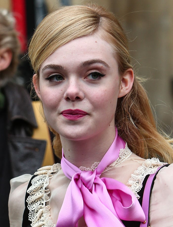 Showing how to wear a pussy bow scarf, Elle Fanning clips her hair back for the Gucci catwalk show