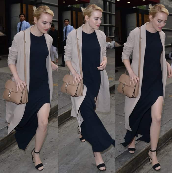 Emma Stone wears a navy dress layered under a nude color trench coat