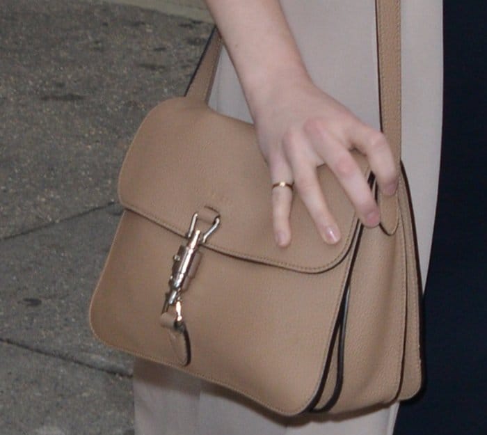 A close-up of Emma Stone’s Gucci "Jackie" bag in a timeless nude shade, featuring the brand’s signature piston closure and sleek, structured silhouette—an effortlessly chic addition to her ensemble