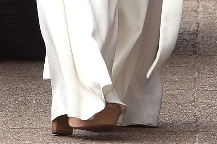 Nicole Scherzinger's choice of sand-colored suede Aquazzura "Kaya" platform sandals not only complements her white ensemble but also provides a significant height boost with their chunky heels and peep-toe design