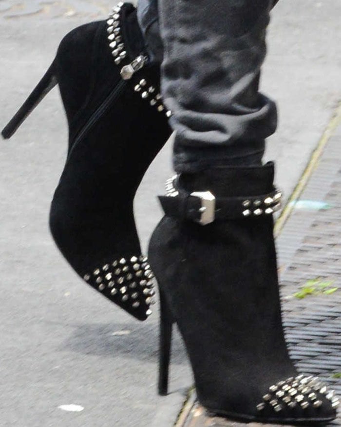 Paris Hilton adds edge to her Milan look with Philipp Plein's black suede studded booties, featuring buckle details and a sharp stiletto heel