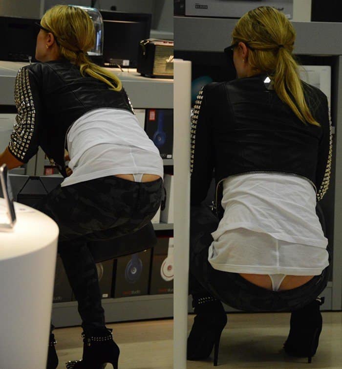 Paris Hilton's chic look took a revealing turn as she bent down while browsing in Milan, showing off her studded Philipp Plein booties and a peek of her white thong beneath her camouflage skinny jeans