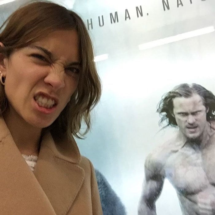 Alexa Chung takes a photo beside her boyfriend Alexander Skarsgard's "The Legend of Tarzan" poster