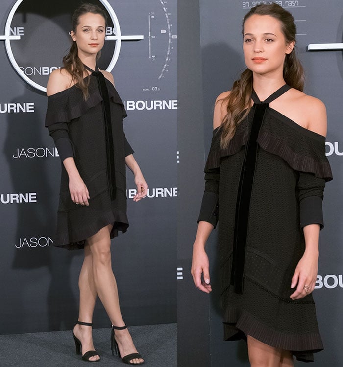 Alicia Vikander poses on the black carpet in a ruffled black Proenza Schouler dress