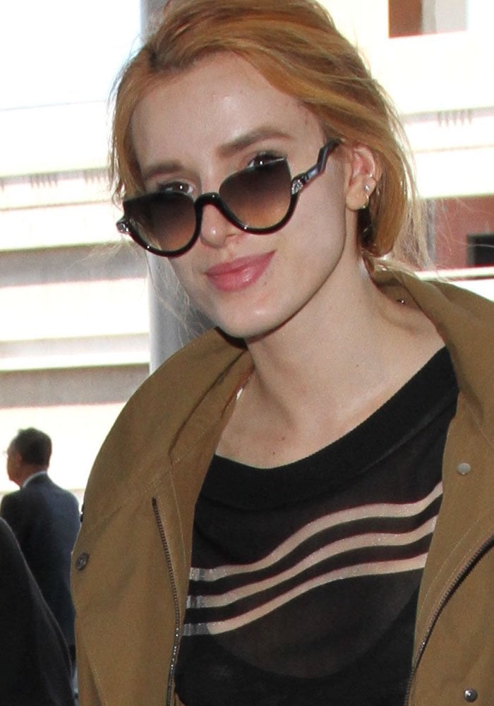 Bella Thorne clips her hair back as she arrives at the Los Angeles International Airport