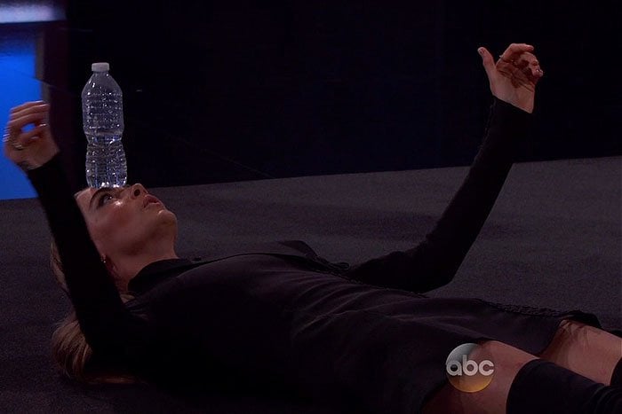Cara Delevingne lays on the floor with a water bottle on her head during a TV appearance