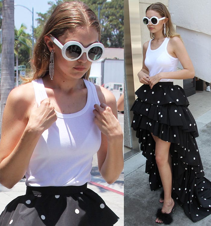Gigi Hadid wears a white tank top tucked into a ruffled polka-dot-print skirt