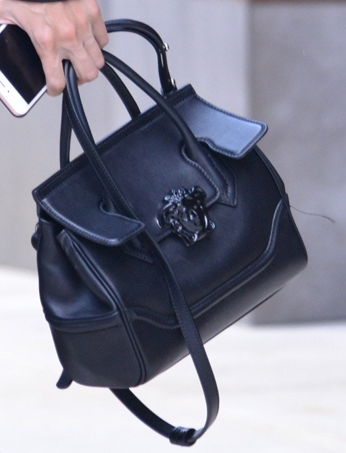 Gigi Hadid carries an iPhone and a Versace tote bag