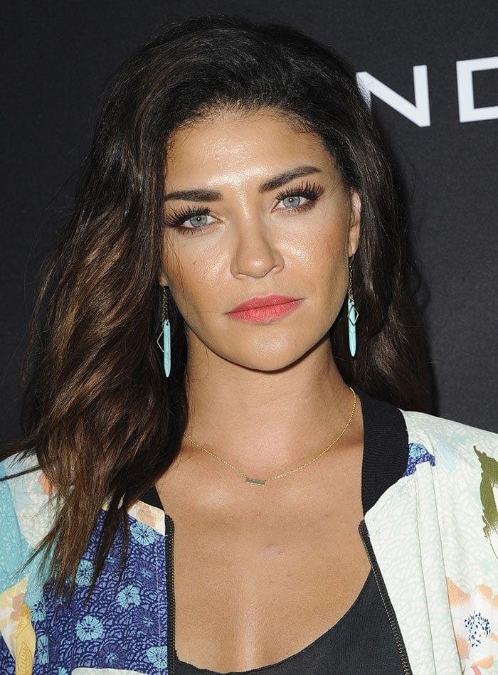 Jessica Szohr complements her voluminous waves with bold lashes, a coral lip, and minimal jewelry, including delicate turquoise earrings and a dainty gold necklace
