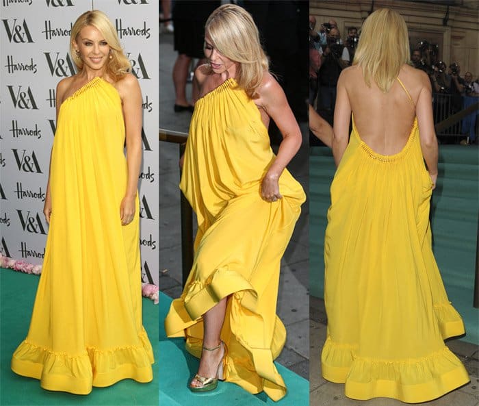 Kylie Minogue dazzled at the V&A Summer Party in a vibrant yellow Stella McCartney 'Astrid' halter dress featuring a pleated asymmetrical neckline, a one-strap open back, and a floor-length hem, complemented by smokey eyes, glossy pink lips, and colored stone earrings