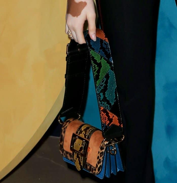 Winnie Harlow carried a bold Burberry patchwork bag featuring leopard print, snakeskin, suede panels, and a wide multicolor python strap with a signature buckle detail