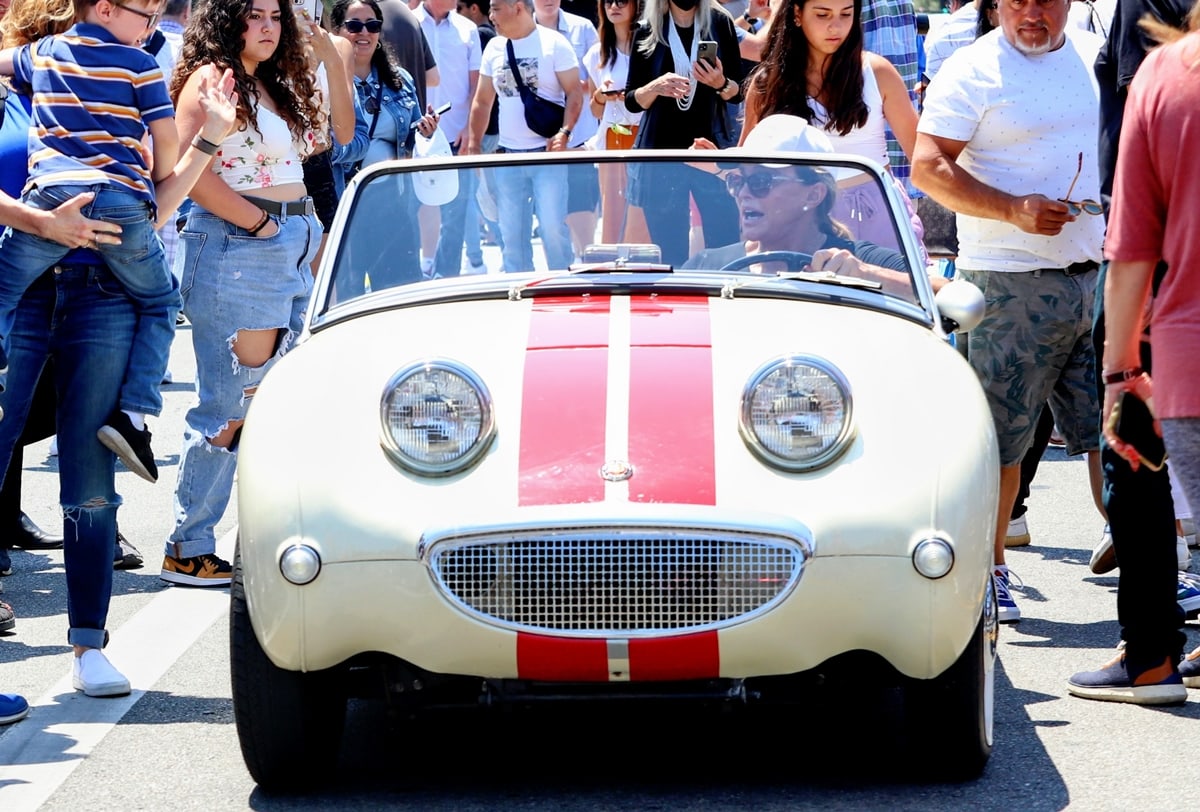 Caitlyn Jenner drives a white and red Austin-Healey Bugeye Sprite small open sports car