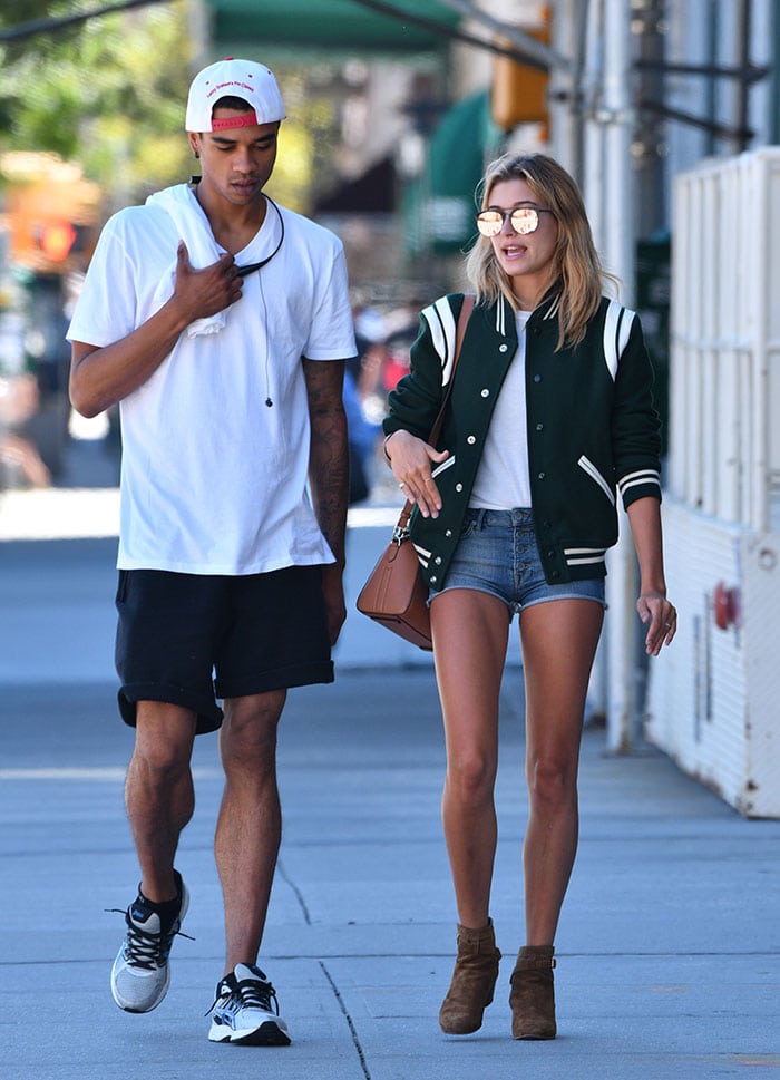 Hailey Baldwin wears Armani denim shorts with a Saint Laurent varsity jacket