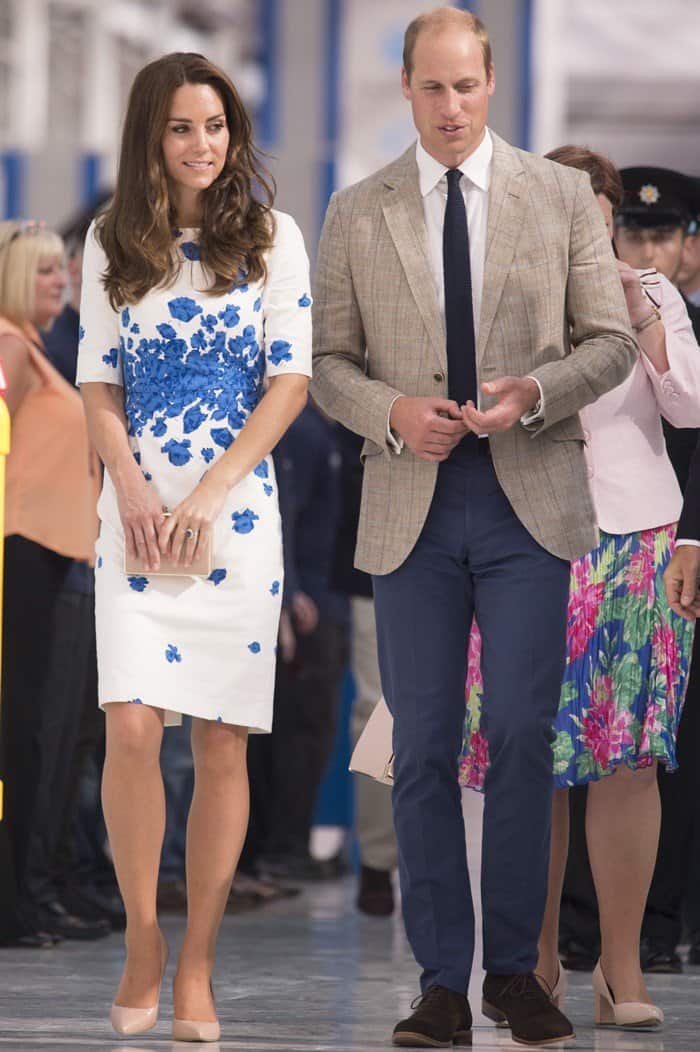 Kate Middleton radiates elegance in a white L.K. Bennett dress adorned with vibrant blue poppies, perfectly paired with nude pumps during a charity visit with Prince William