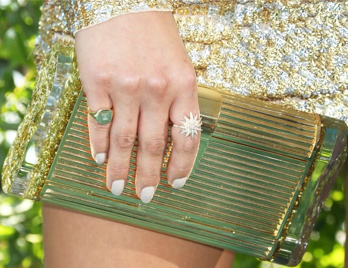 Shay Mitchell holds a gold Edie Parker clutch