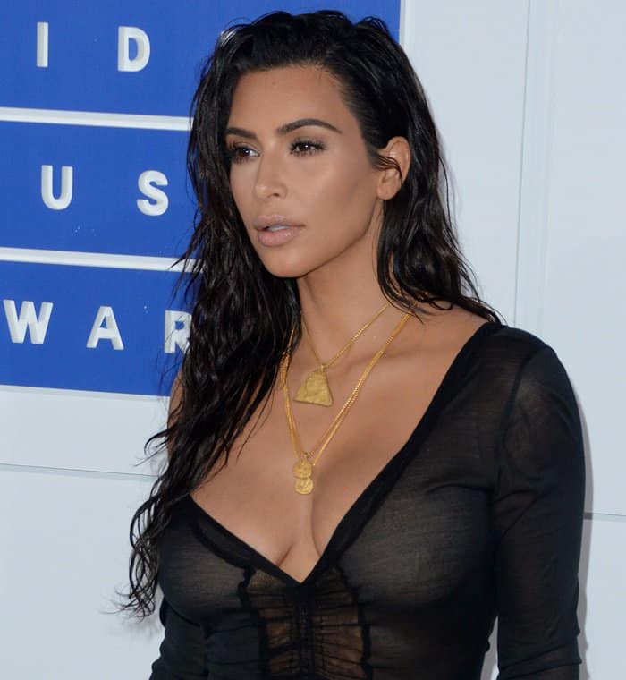 Kim Kardashian complements her sultry wet-look hairstyle with layered gold necklaces