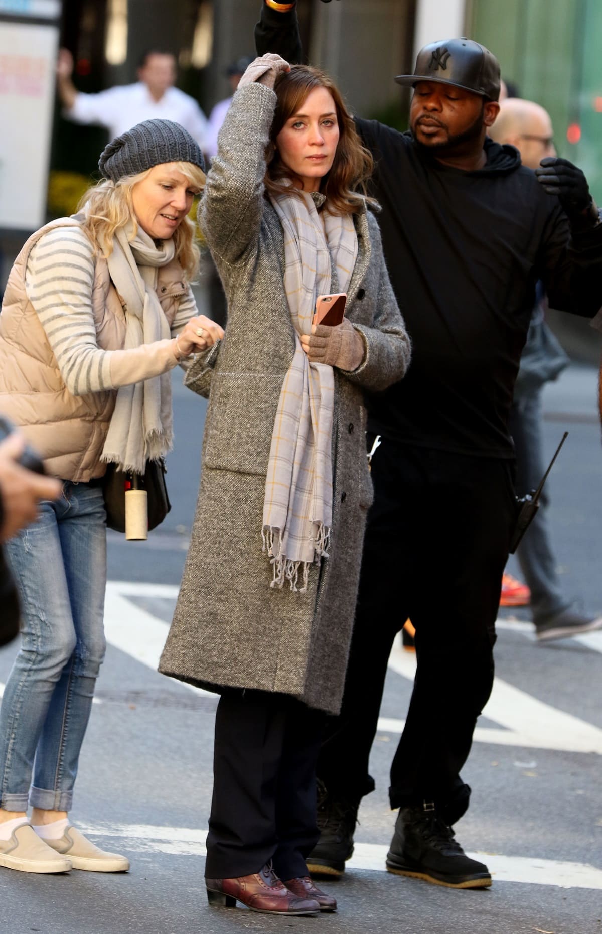 Emily Blunt, dressed in character as Rachel Watson, wears a long tweed coat, plaid scarf, and weathered oxford-style shoes while filming The Girl on the Train in New York City on November 4, 2015