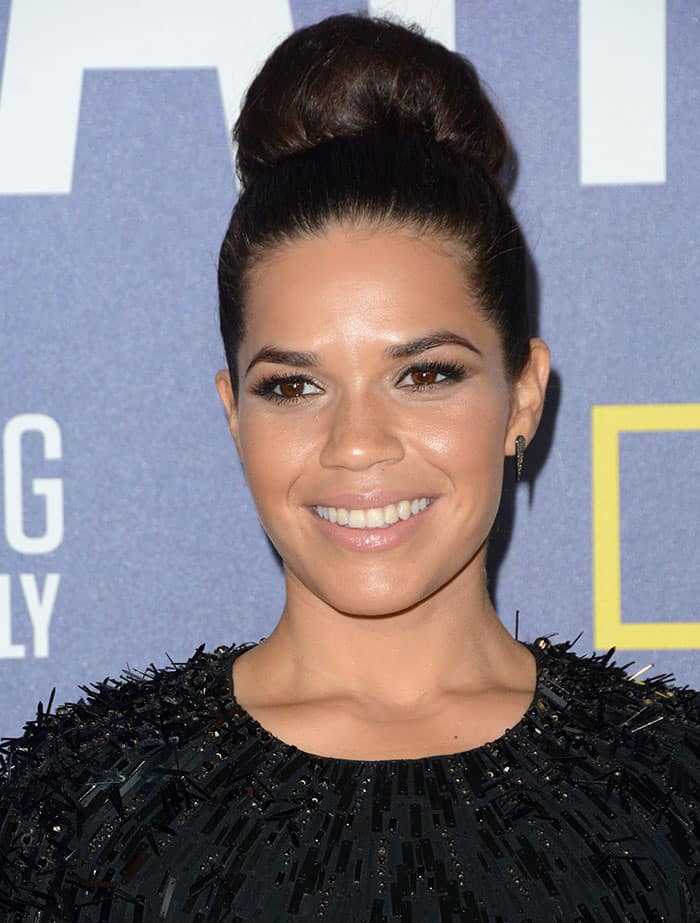 America Ferrera accessorized with a high bun and smudged smokey eye completed with a nude lip