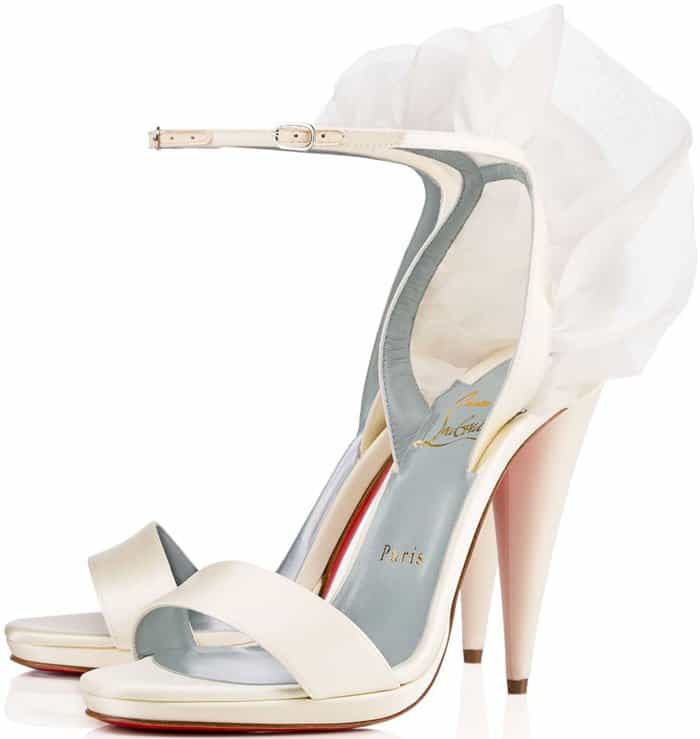 Wispy wings fly at the heel of a striking ankle-strap sandal lifted by a architectural cone heel