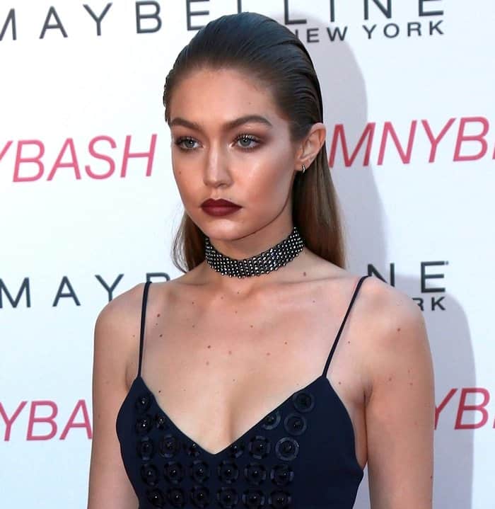 Gigi Hadid exudes fierce elegance with her sleek hair, bold choker, and deep berry lip at the Maybelline New York Beauty Bash