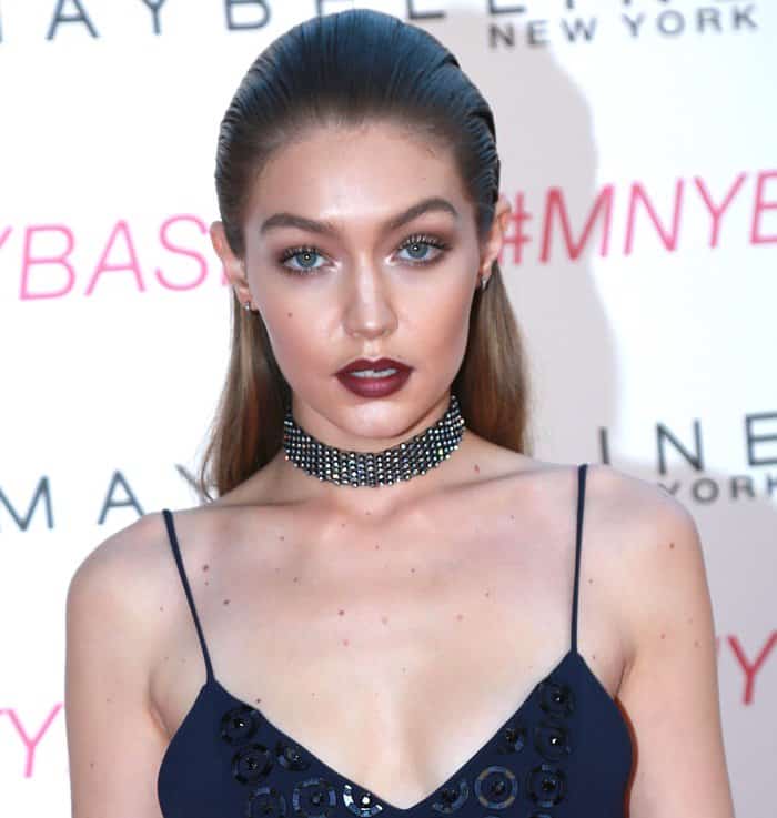 Gigi Hadid's look is elevated by her sleek, slicked-back hair paired with bold, dark berry lips and subtle eye makeup