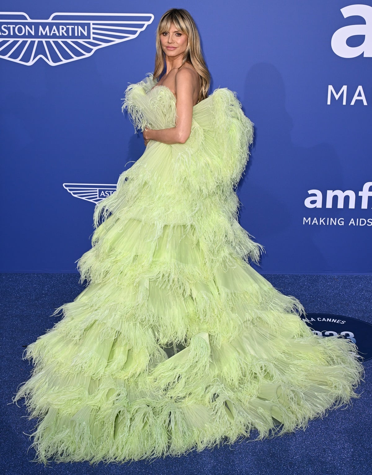 Heidi Klum turned heads in a vibrant green mini dress from the Georges Hobeika SS23 Couture collection boasting a striking train adorned with layers and tasseled embellishments