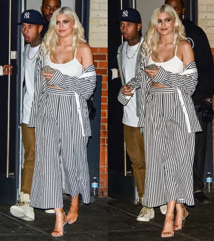 Kylie Jenner steps out in New York with her boyfriend Tyga, wearing a striped pajama-inspired outfit from the Kendall + Kylie collection, paired with Yeezy "Lucite" sandals, and holding an embroidered Gucci iPhone case