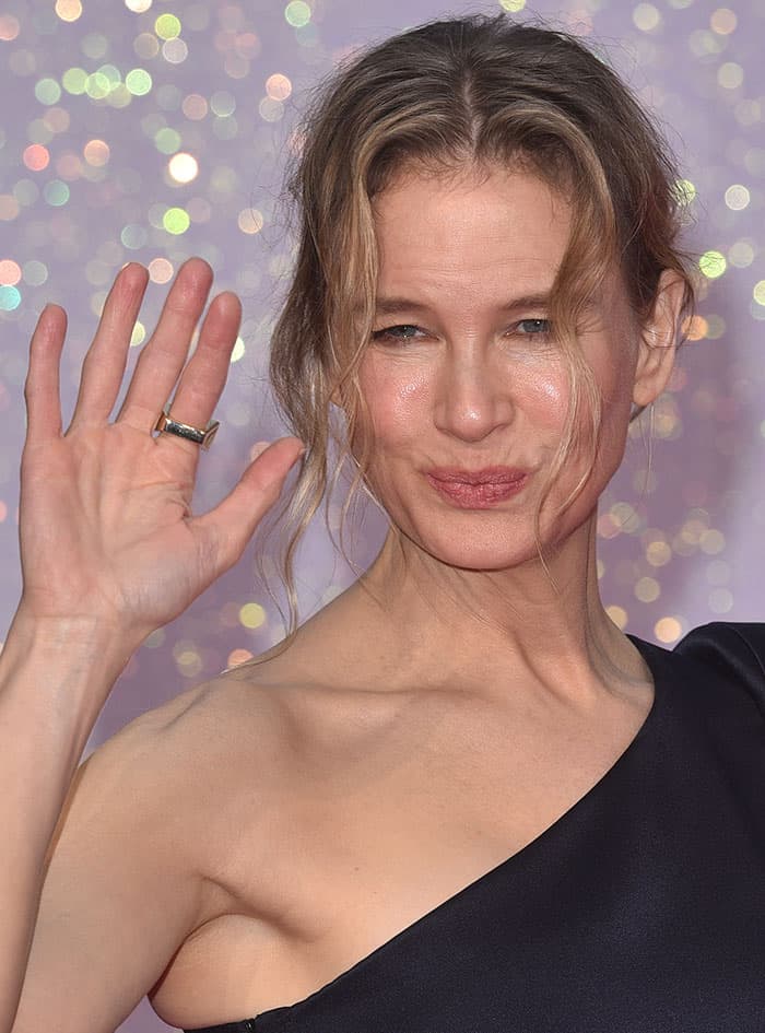 Renee Zellweger's hair, styled in a relaxed up-do, allowed loose strands to softly frame her face, which was enhanced with subtle makeup, emphasizing her natural beauty