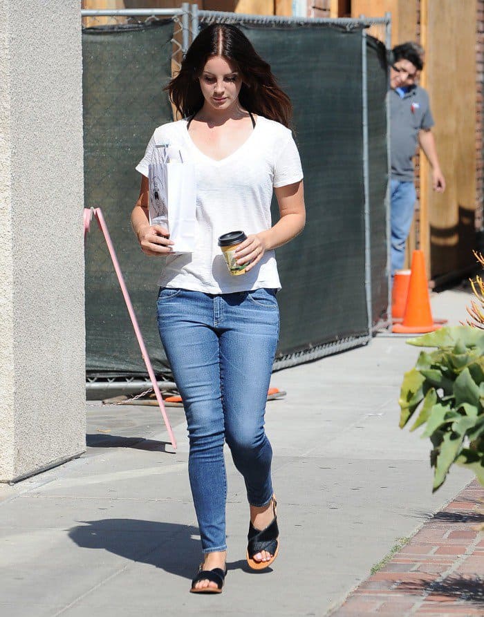 Lana Del Rey grabs coffee wearing casual blue jeans and a white shirt