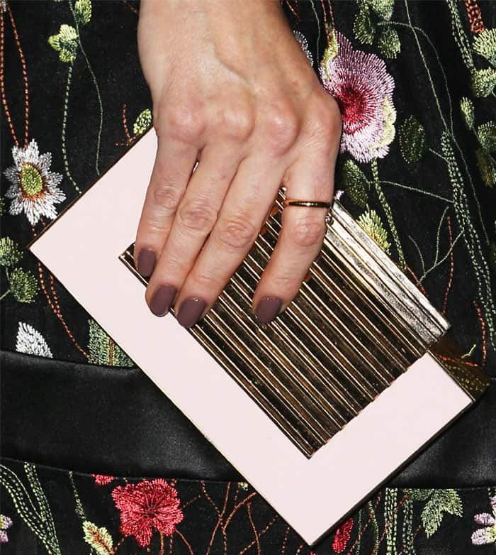 Bellamy Young holds on to a chic "East Stack" clutch in pink/rose gold by Lee Savage