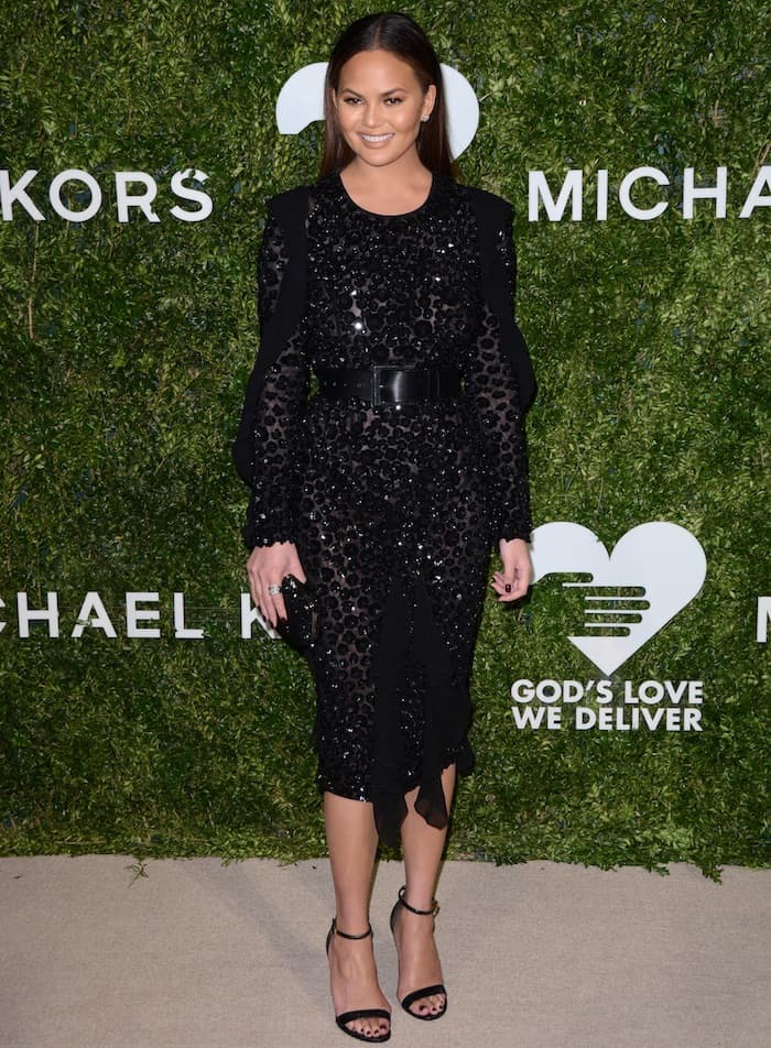 Chrissy Teigen flashes some skin in an embellished Michael Kors dress for the God's Love We Deliver Golden Heart Awards