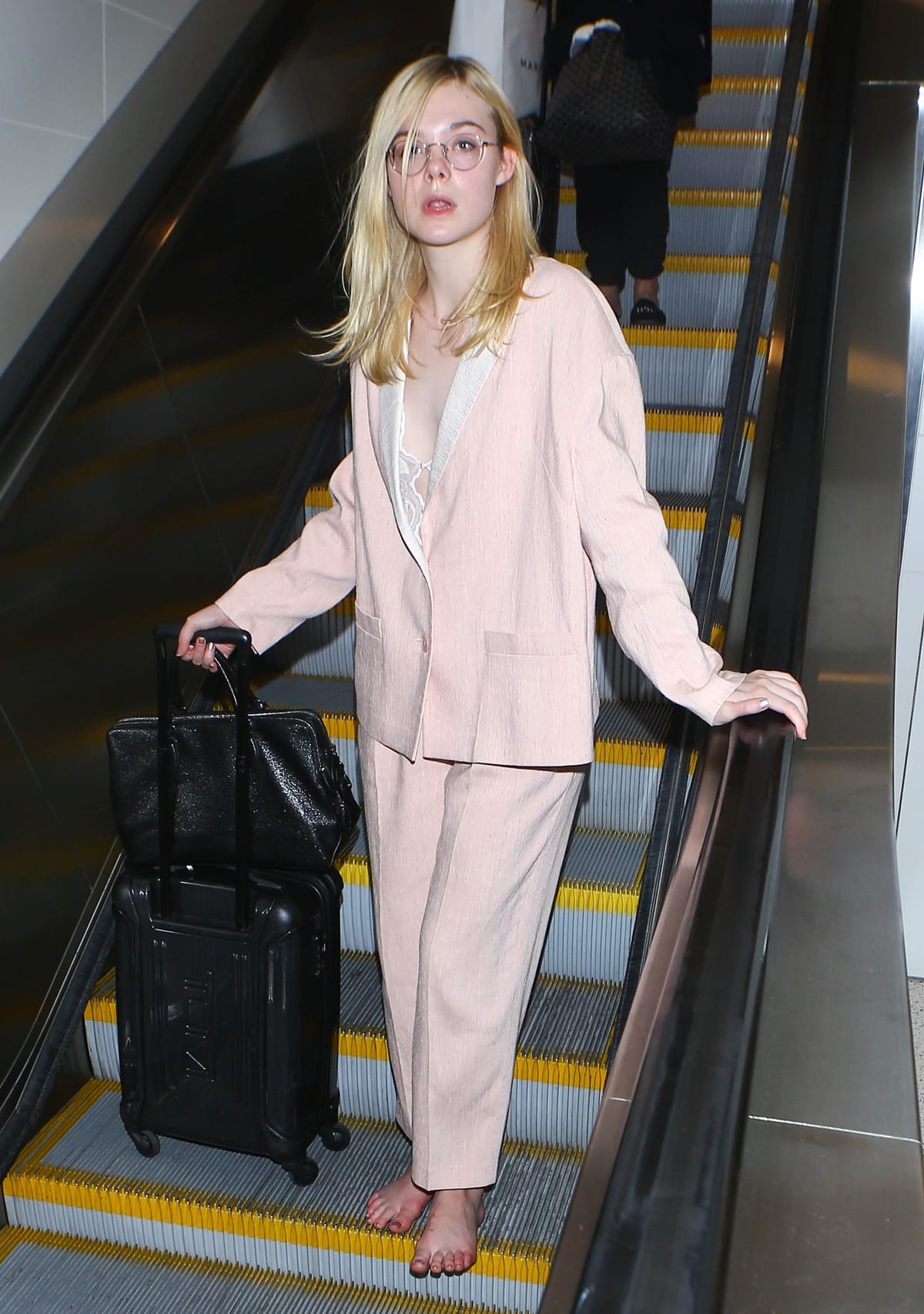Elle Fanning was photographed arriving at the airport in a baggy pink pantsuit and glasses, without any shoes on her feet at LAX International Airport
